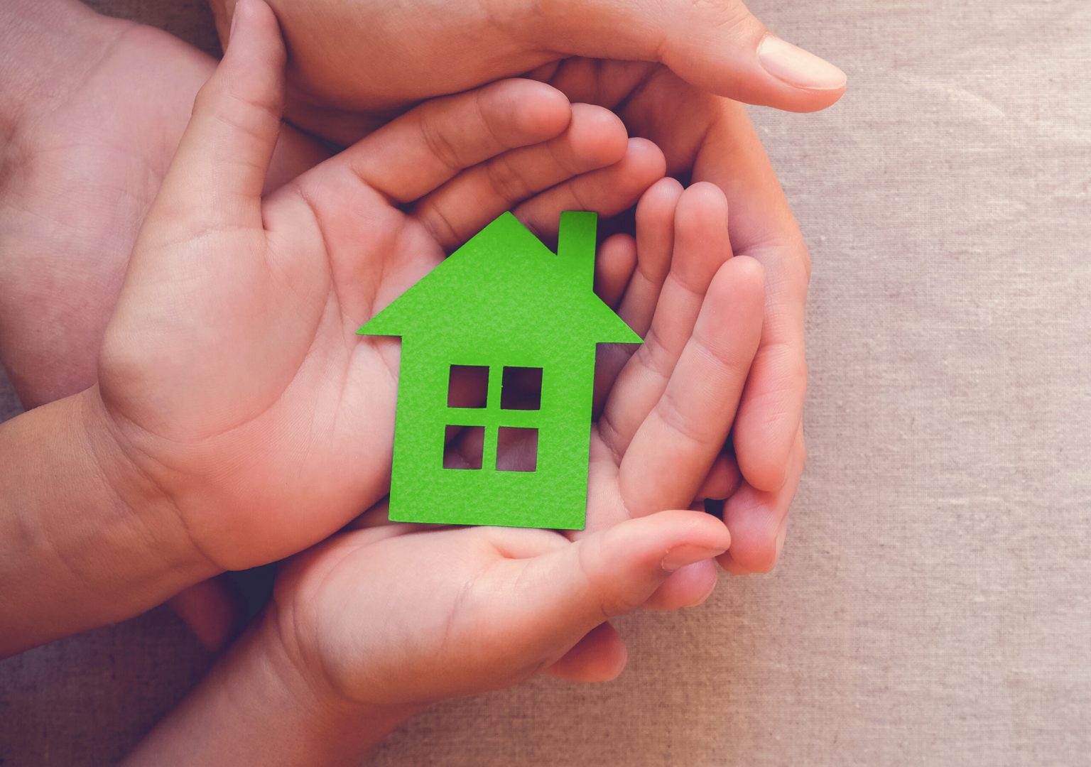 Adult and child hands holding green paper house, eco house concept